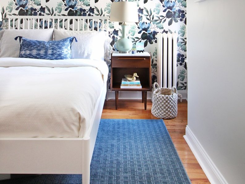 Blue area rug under a white bed in a tropical bedroom